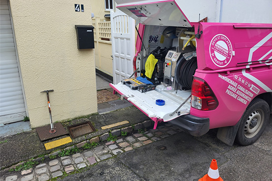 Pick-up d'intervention avec le coffre ouvert devant la maison d'un client pour une prestation de débouchage de canalisation. Regard ouvert grâce à un gros aimant.